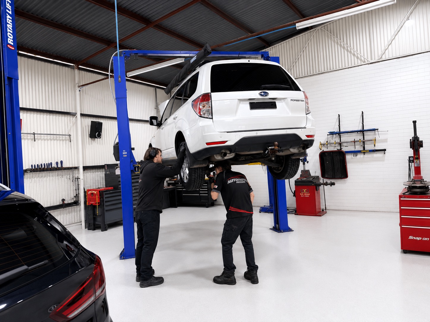 Two Automotive Insight technicians working under a Subaru Forester on the hoist, Shenton Park